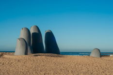 a-sandy-beach-with-a-group-of-large-rocks-sticking-out-of-the-sand.jpg a sandy beach with a group of large rocks sticking out of the sand